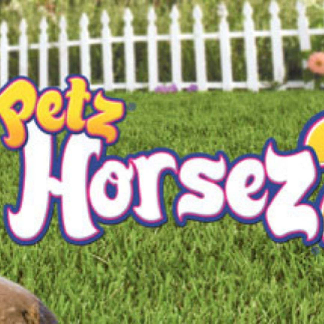 A graphic from the game Petz Horsez 2. It shows a grassy field with a white picket fence in the background. In the center there is text that says Petz Horsez. The 2 after Horsez is cut off.