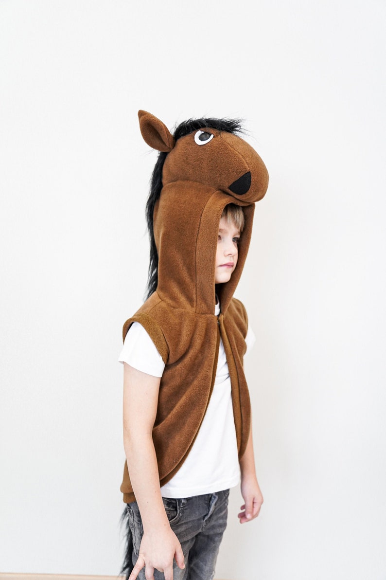 A kid in a brown horse costume that looks like a vest with a horse head attached.