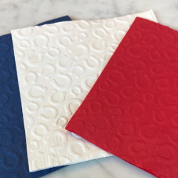 Horseshoe napkins from NapkinBoss on Etsy. It shows a blue napkin, white napkin, and red napkin with raised looking horseshoes.