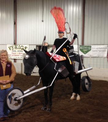 A horse wearing a motorcycle costume with a rider who has a flame mohawk on.