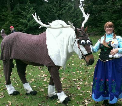 A girl dressed like Anna from Frozen standing with a horse dressed up like Sven the reindeer from the movie Frozen.