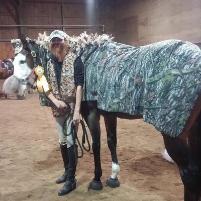 A horse dressed in camouflage standing next to a rider dressed as a Duck Dynasty character.