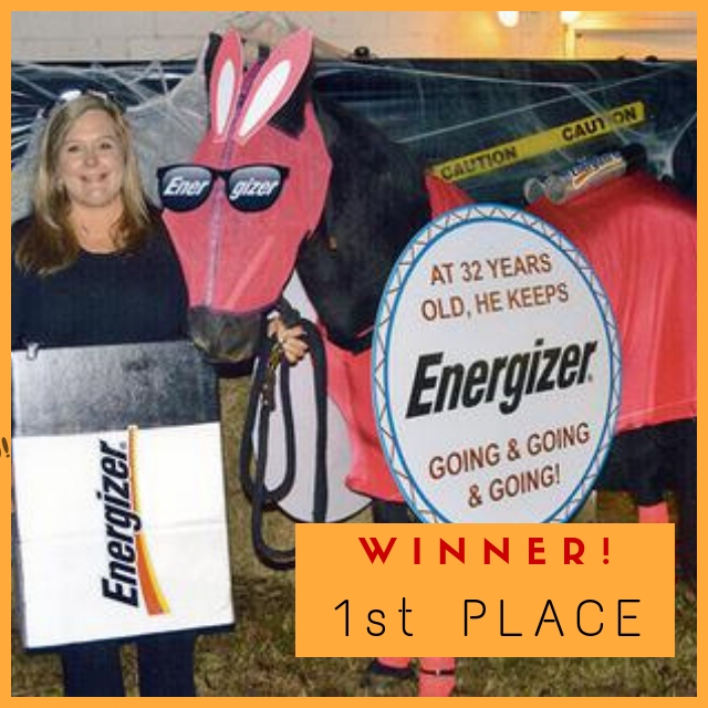 A horse dressed up as the Energizer bunny being held by a woman wearing a costume that makes her look like and Energizer battery.