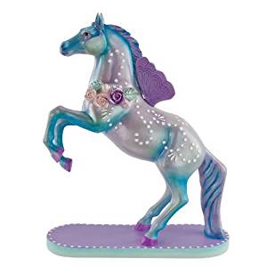 The Trail of Painted Pont collectable Happy Trails Flight of Fancy. It shows a silver horse with blue highlights on its head, neck, and legs rearing on a purple and blue base. The horse has purple butterfly looking wings attached near its withers and has white dots across its body. There is also a wreath of purple, teal, and cream roses around its neck. The horse's mane and tail are also blue and purple. The horse's hooves are purple.