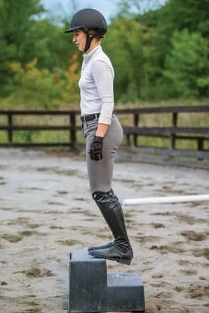 Image from Practical Horseman that shows a rider stretching on a mounting block
