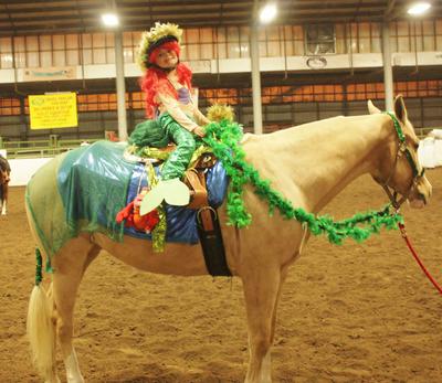 A girl dressed as a mermaid on a horse wearing a costume that resembles the sea.