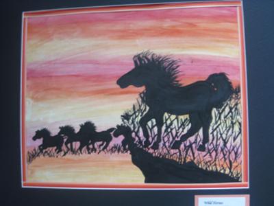 A painting of a herd of horses galloping at sunset. One horse is standing on a rock looking down at the others. All the horses are black silhouettes. There are trees behind the horse on the rock.