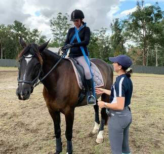 Image from the Eventing Physiologist of a woman riding a horse with an instructor