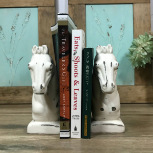 Two white horse heads holding books between them.