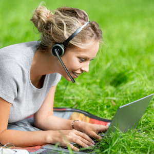 Girl looking at her computer with a headset on.